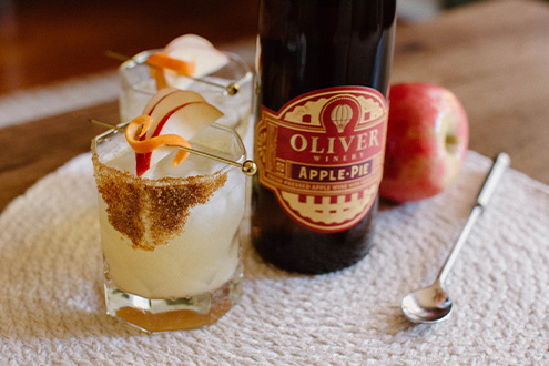 A Caramel Apple Old Fashioned in a lowball glass with a brown sugar rim and sliced apple garnish.
