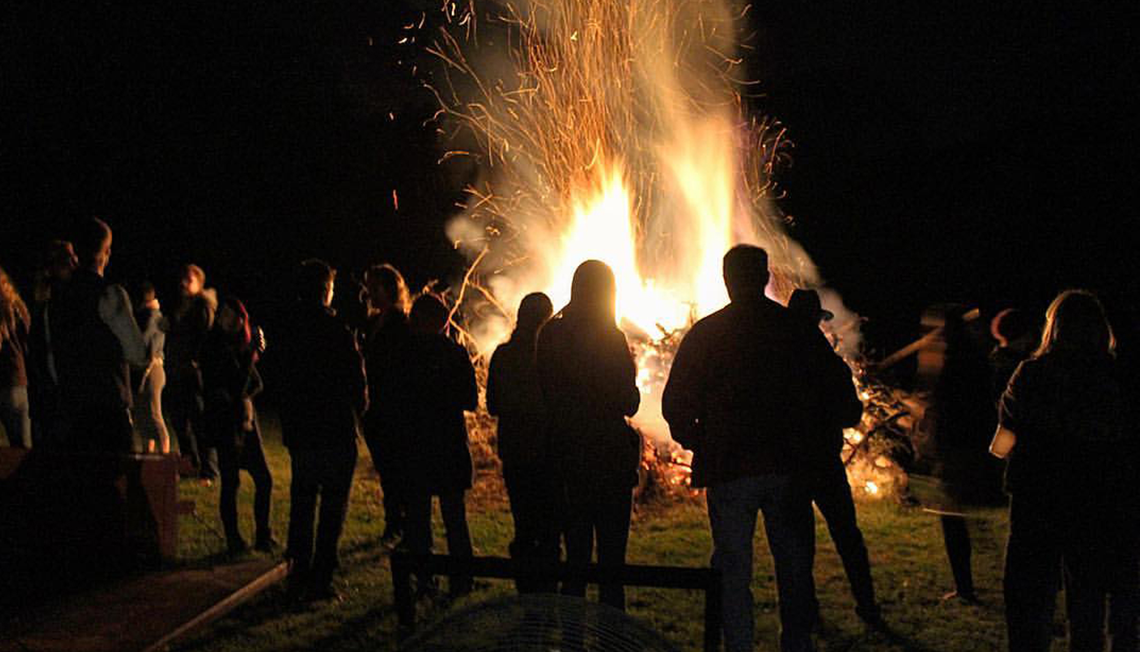 Party guests stand near a giant vine bonfire at Creekbend Vineyard. 