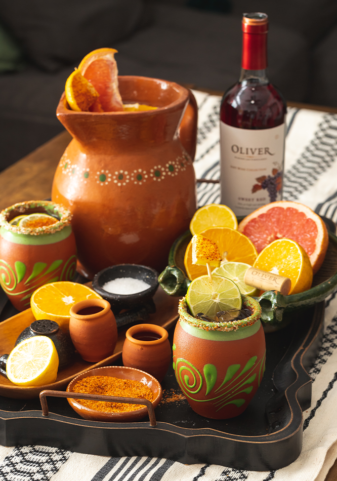 Ceramic cup and pitcher filled with red wine and citrus fruit