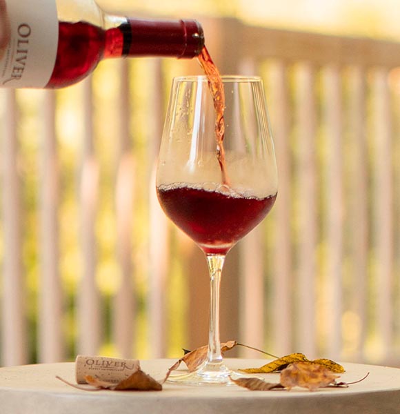 A stemmed glass filled with ruby-red colored Oliver Winery Sweet Red, a best-selling wine.