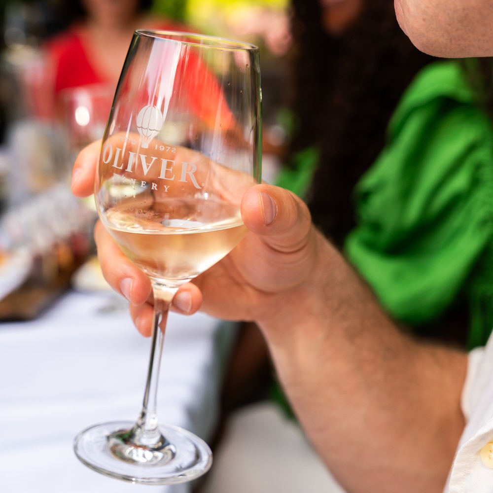 Summer photo of Oliver Tasting Room patio surrounded by lush gardens and people