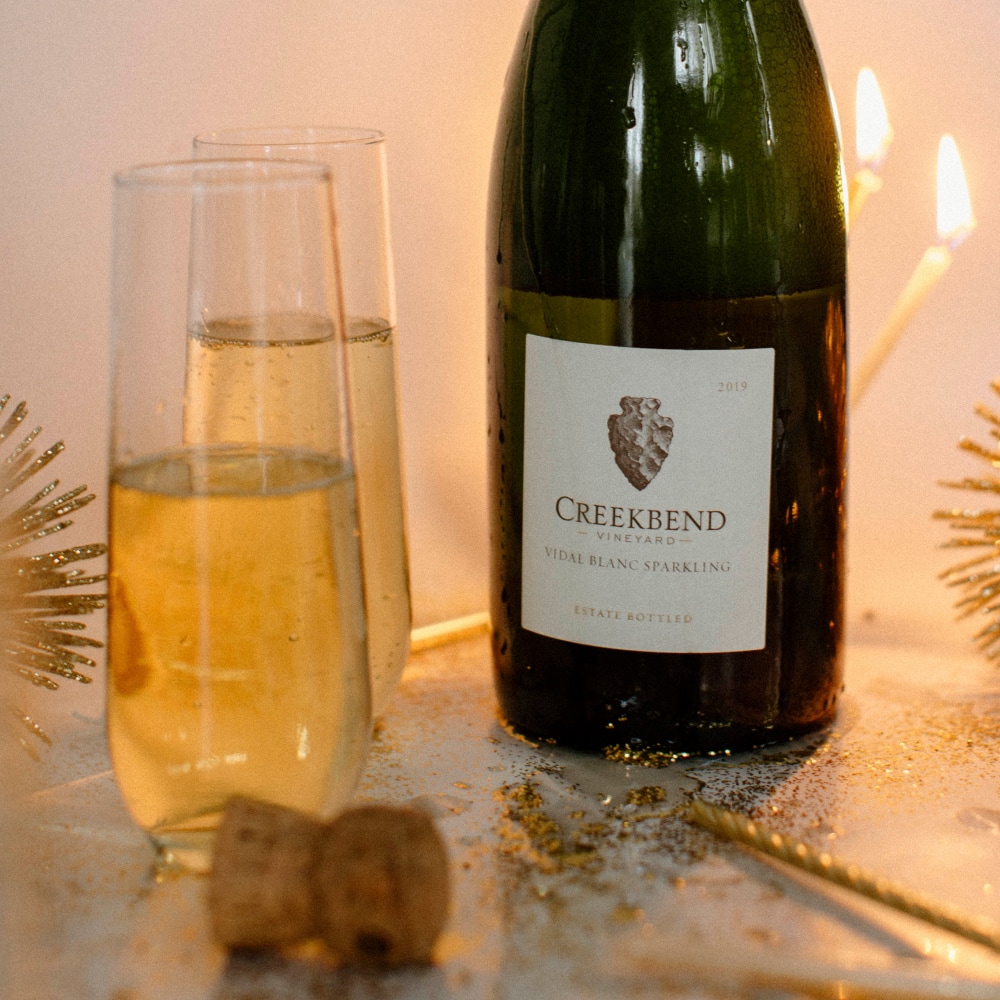 Creekbend Vidal Blanc Sparkling on the counter next to two glasses ready to be enjoyed.