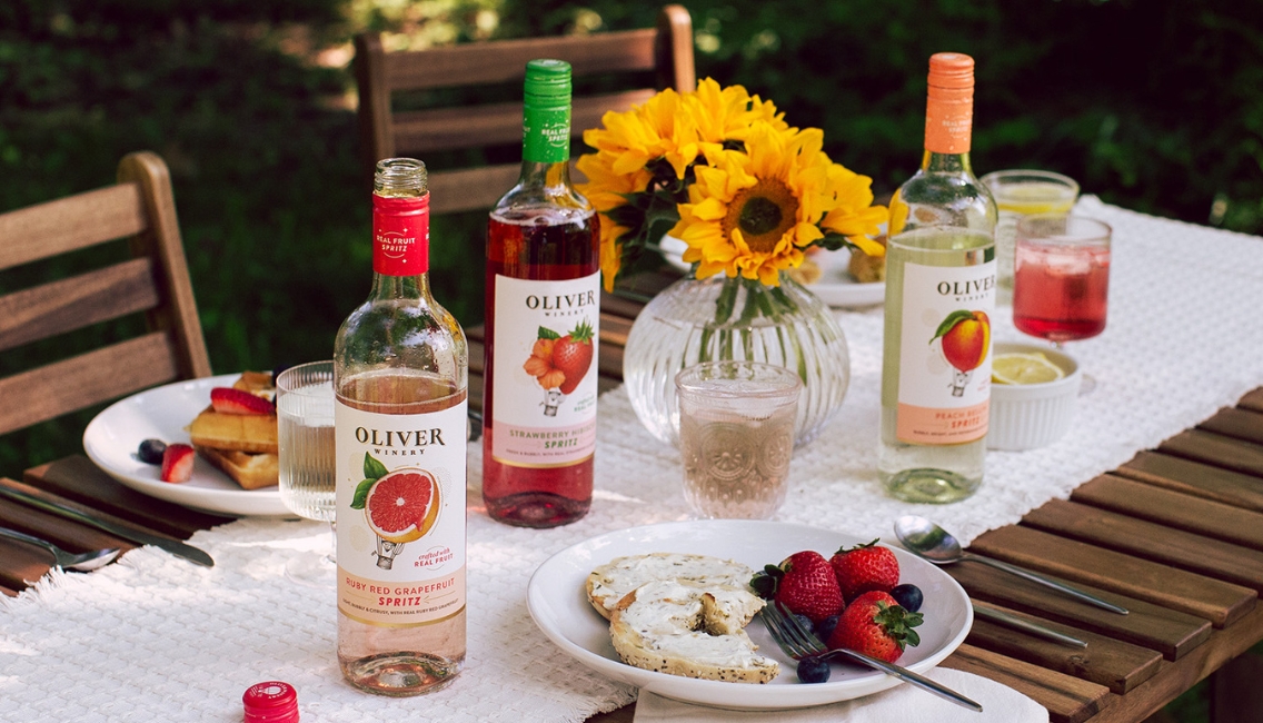 Oliver's New Spritz Flavors Ruby Red Grapefruit, Strawberry Hibiscus, and Peach Bellini in an outdoor brunch setting