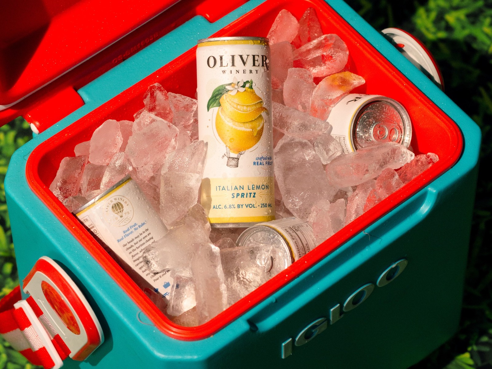 Oliver Winery Italian Lemon Spritz cans on ice in an open teal and red cooler on the grass