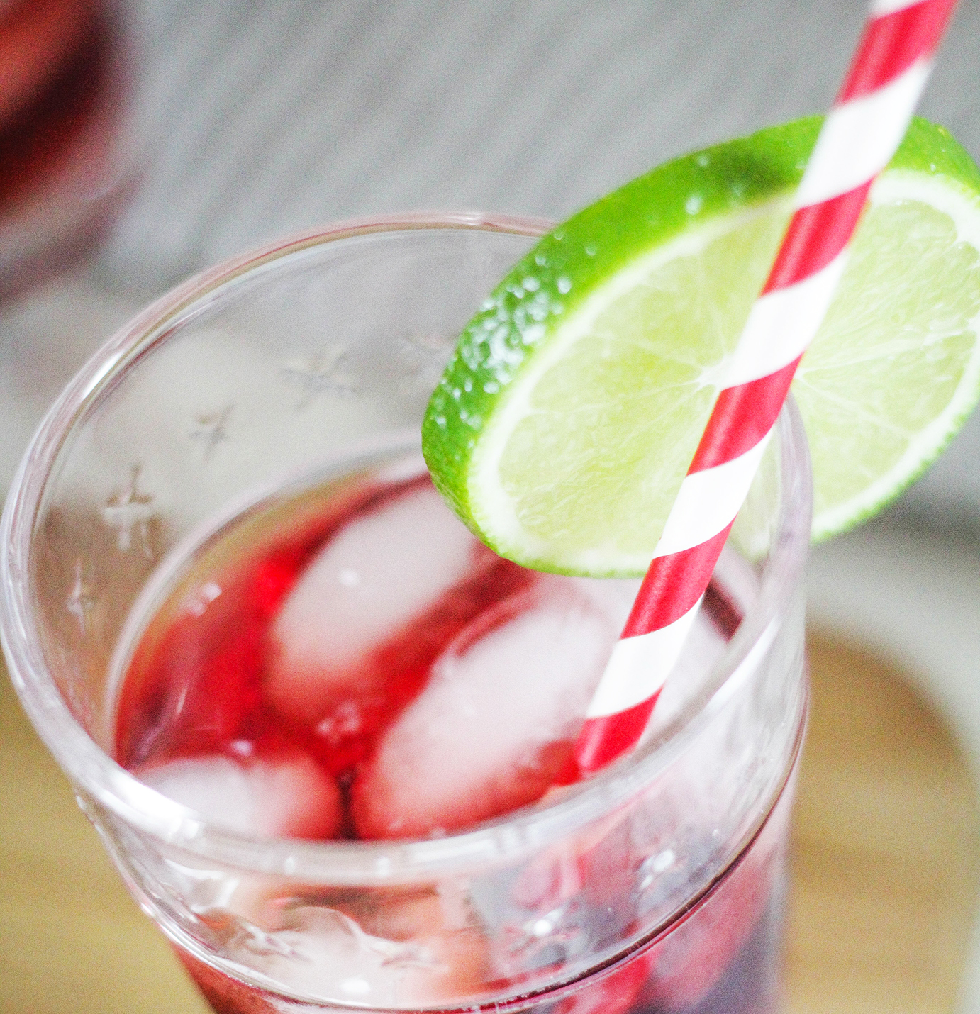 Soft Red Lime sweet red wine in a glass with ice and a red-and-white striped straw